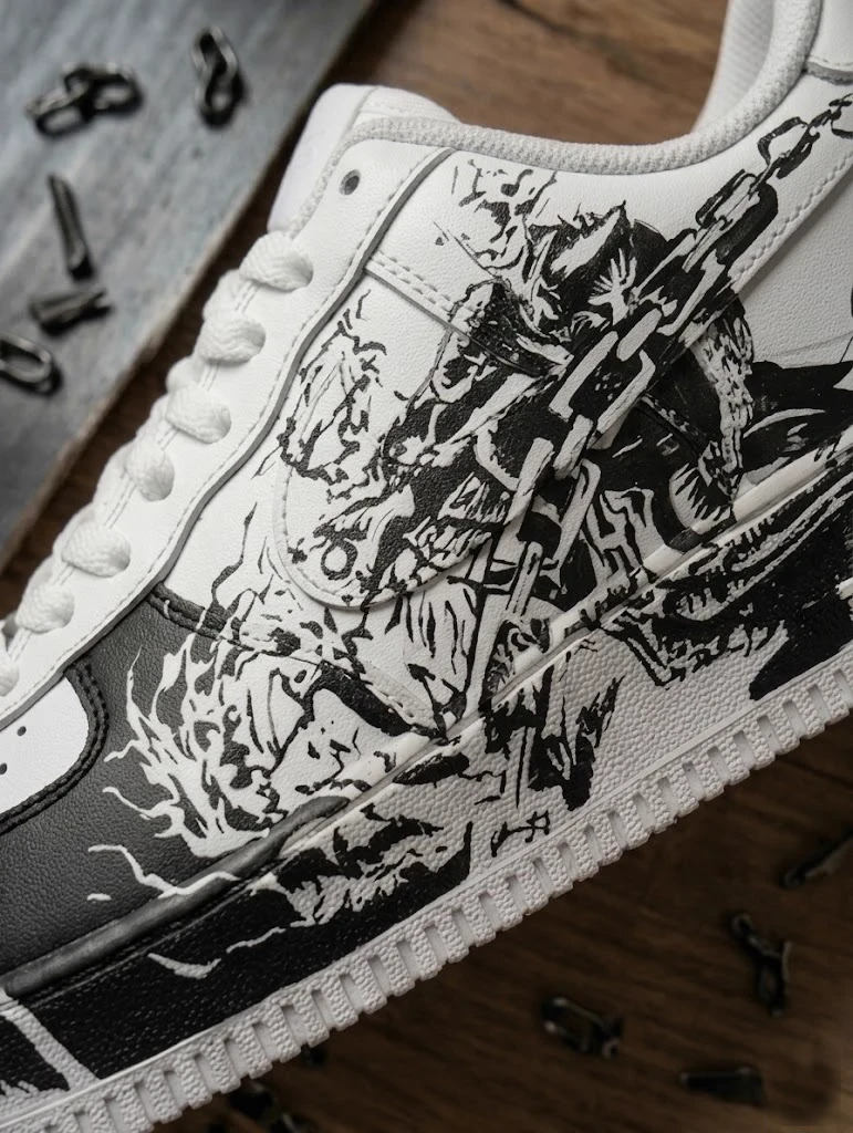Hand-inked artwork running across the toe and quarter panels of a white leather pair
